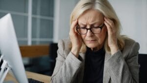 Woman at desk with head in her hands