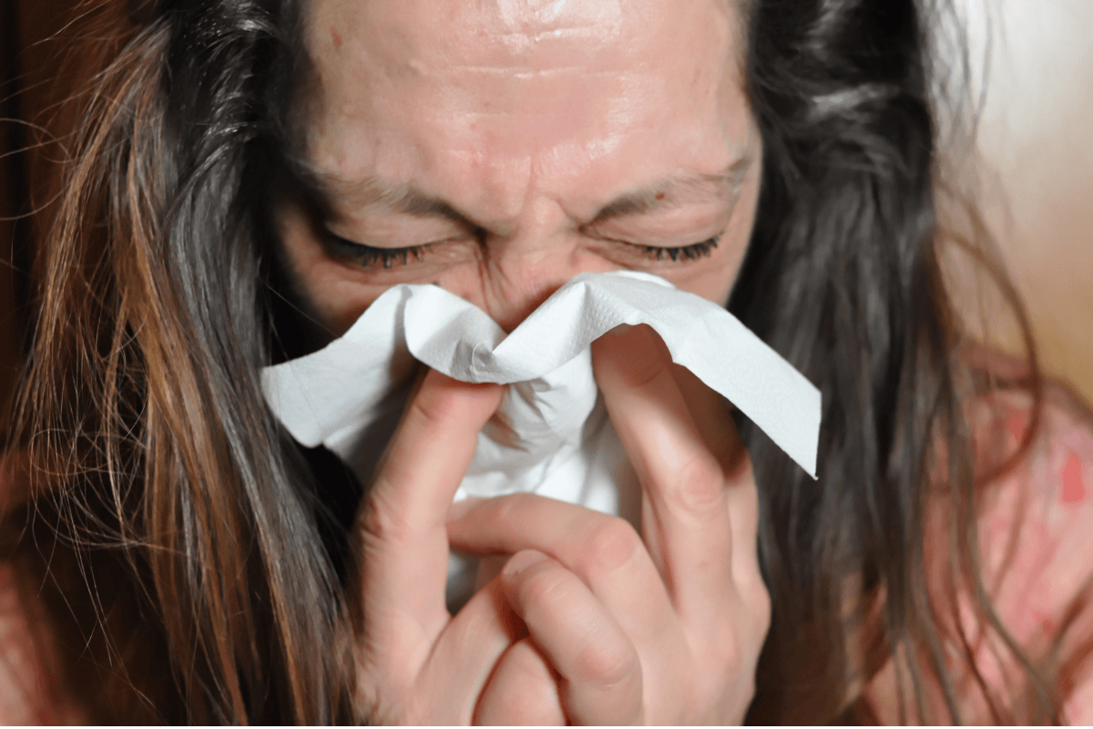 sickness absence woman sneezing into a tissue